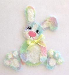 a small stuffed animal with a bow on it's head and eyes, sitting up against a white background