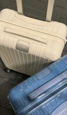 two pieces of luggage sitting on the floor next to each other, one blue and one white