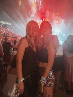 two women standing next to each other with fireworks in the background