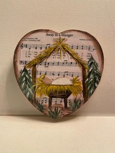 a heart shaped box with a nativity scene on it and sheet music in the background