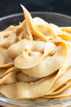 a glass bowl filled with pasta noodles on top of a black countertop next to a wooden spoon