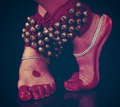 a woman's feet wearing red shoes with gold beads on them