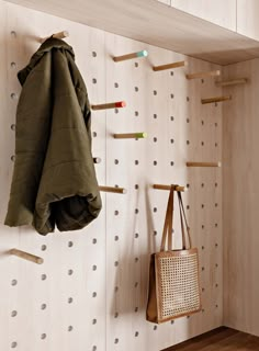 a coat rack and purse hanging on a wall with pegs in the closet next to it