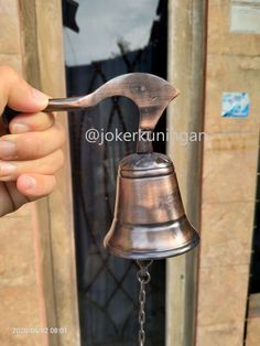 a person holding a metal bell in front of a door