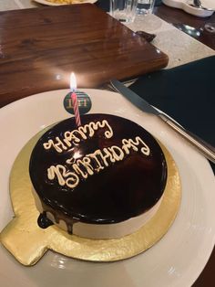 a chocolate birthday cake with lit candles on a plate