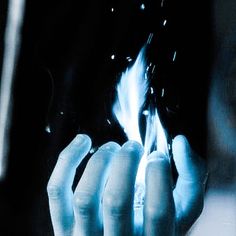 a person holding something in their hand with blue flames coming out of it's fingers