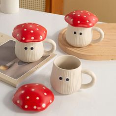 three ceramic mushrooms sitting on top of a table next to a book and coffee cup