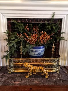 a gold tiger statue sitting in front of a fire place next to a potted plant