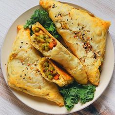 two pastries on a plate with greens and seasoning next to eachother