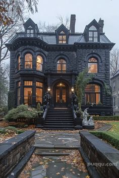 a large black house with many windows and steps leading up to the front door area