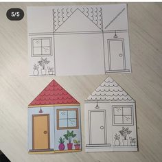 cut out paper houses on top of a wooden table next to scissors and pencils