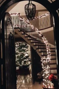 the stairs are decorated with christmas lights and garlands for an elegant entrance to this home