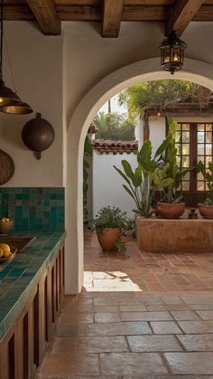 an outdoor kitchen with potted plants on the counter and tile flooring in between two archways