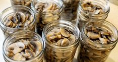 several jars filled with mushrooms sitting on top of a table