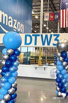 two blue and silver balloons are in the middle of an indoor area with amazon's logo