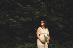 a pregnant woman standing in front of trees