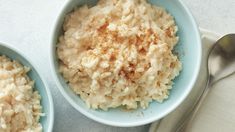 two blue bowls filled with rice on top of a white table next to a spoon