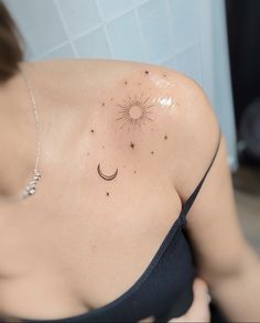 a woman with a sun and moon tattoo on her upper arm, behind her shoulder