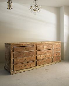 an old wooden dresser in a room with a chandelier hanging from the ceiling