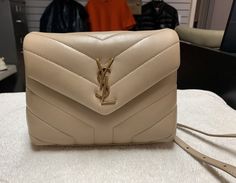 YSL Saint Laurent Toy Loulou Beige Crossbody Bag Height: 5.5" Length: 7.5" Depth: 3" Strap drop: 20-23" Gold hardware Leather shows some wear on the corners. Has some creases on the leather. Gold hardware has scratches. Inside has dried up hard stains. Comes with dust bag Saint Laurent Toy Loulou, Beige Crossbody Bag, Ysl Saint Laurent, Crossbody Shoulder Bag, Gold Hardware, Leather Crossbody, Bags Handbags, Saint Laurent, Crossbody Bag