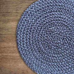 a round blue rug on top of a wooden floor next to a black and white cat