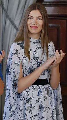 a woman standing in front of a wooden door holding her hands up to the side