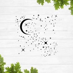 the moon and stars are flying in the sky above some green leaves on a white wooden background