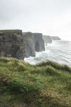 the cliffs are covered in green grass by the ocean