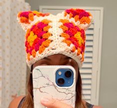 a woman taking a selfie with her cell phone wearing a crocheted cat hat