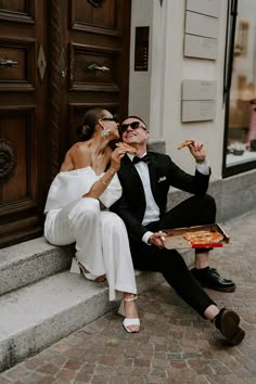 a man and woman are sitting on the steps eating pizza while wearing formal attire,