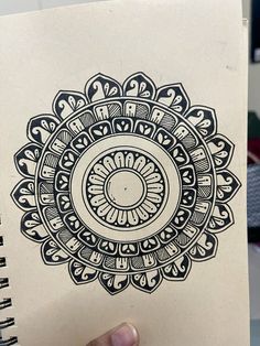 a hand holding a notebook with an intricate design on it