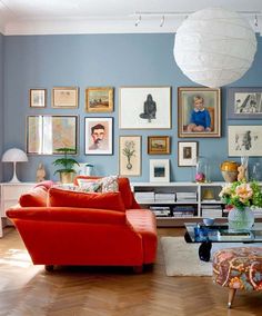 a living room with blue walls and pictures on the wall above the red couches