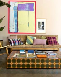 a living room filled with furniture and paintings on the wall above it's coffee table