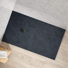 a bathroom with white walls and wood flooring next to a black bathtub in the corner