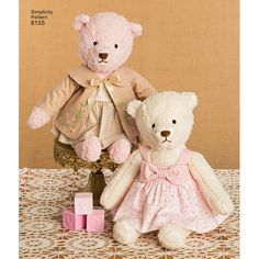 two teddy bears dressed in pink sitting next to each other on a lace tablecloth