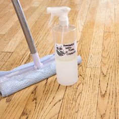 a bottle of hand sanitizer sitting on top of a wooden floor next to a cleaning brush