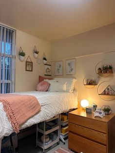 a small bedroom with a bed, dresser and window in it's center area