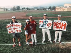 some baseball players are holding up signs and posing for a photo in front of the field