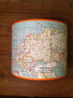 a lamp shade that is hanging on a wooden wall with a map printed on it