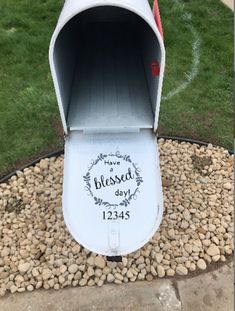 a white mailbox sitting on top of a gravel covered ground next to a green field