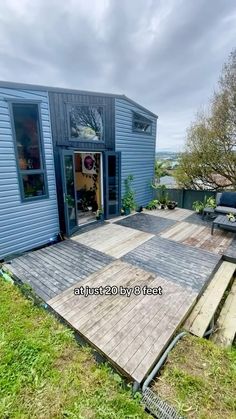 a house with a wooden deck in the middle of it and grass on the ground