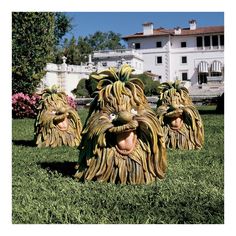 three lion statues sitting in the grass near a building