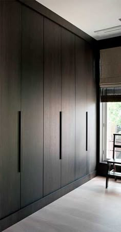 an empty room with dark wood cabinets and white flooring, along with a black chair