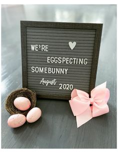 an egg nest with two eggs in it next to a sign that says we're expecting somebunny august