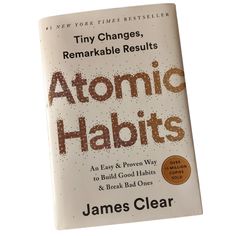 a book with the title atomic habits written in brown and black ink on it