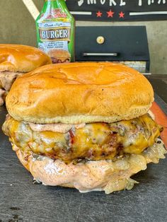 two hamburgers sitting on top of a cutting board next to a bottle of beer