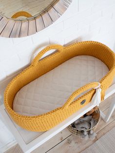 a yellow baby crib sitting on top of a wooden floor next to a mirror