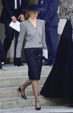 the woman is walking down the steps wearing a black and white suit