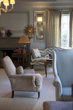 a living room filled with furniture and a fire place under a chandelier in front of a window