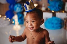 a baby with a crown on his head is smiling at the camera while holding a donut